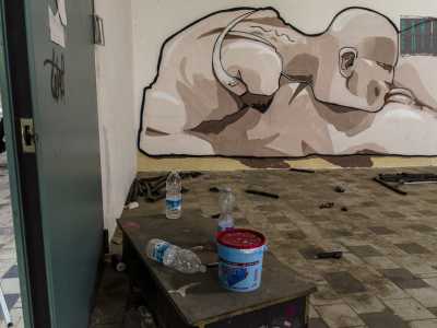 Il murales di un uomo senza braccia dedito all'autoerotismo: in primo piano gli attrezzi usati per disegnarlo